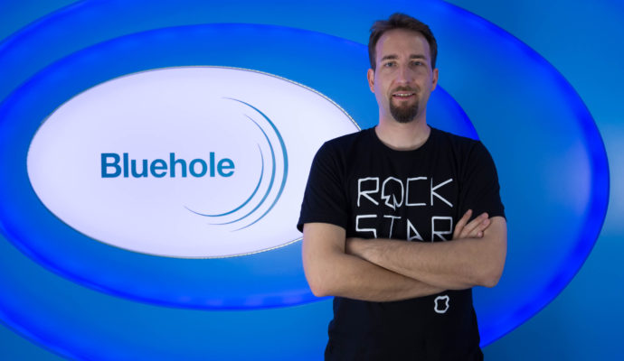 Brendan Green, créateur de PlayerUnknown's Battlegrounds, devant le logo Bluehole