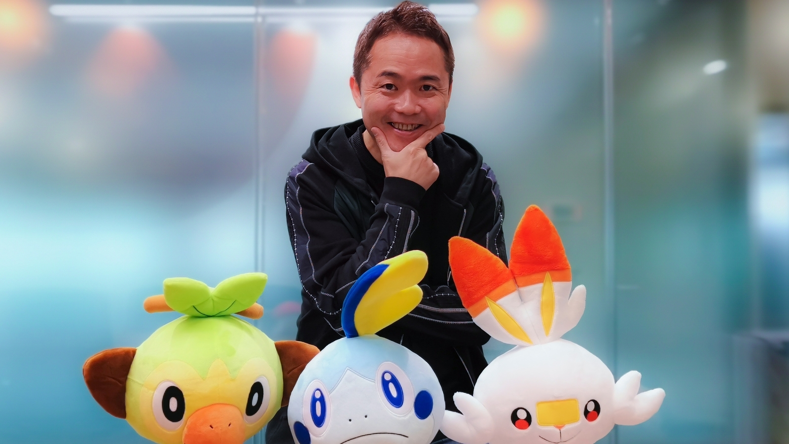 Junichi Masuda en face de peluches des starters de la 8G